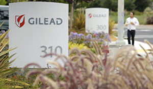 In this July 9, 2015, file photo, a man walks outside the headquarters of Gilead Sciences in Foster City, California. Gilead Sciences produces remdesivir, a drug that has generated excitement for its potential use in treating COVID-19 patients. (AP Photo/Eric Risberg, File)