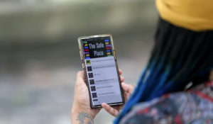 Jasmin Pierre poses for a photo with her smartphone app. Pierre, who survived multiple suicide attempts, doesn't want people struggling alone. She created The Safe Place, a free Black-oriented mental health app that's seen more signups during the pandemic. (AP Photo/Gerald Herbert)