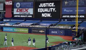 Tampa Bay Rays players warm up near a "Justice. Equality. Now." sign on the videoboard before a Major League Baseball game last week. (AP Photo/Chris O'Meara)