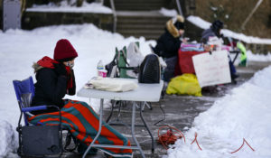 Teachers including Amanda Thornton, left, conduct their classes online from laptops during freezing temperatures outside the Joseph Greenberg School in Philadelphia, Monday, Feb. 8, 2021.  As the CDC prepares to release new guidelines for schools, a mediator will decide if Philadelphia school teachers must return to their classrooms despite safety concerns as the district plans to resume in-person instruction later this month. (AP Photo/Matt Rourke)