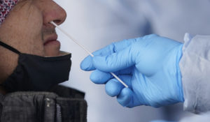 A member of the Salt Lake County Health Department COVID-19 testing staff performs a COVID-19 test outside the Salt Lake County Health Department, Tuesday, Dec. 28, 2021, in Salt Lake City. (AP Photo/Rick Bowmer)