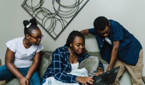 A stock image of a woman and two children looking at a laptop. (Tonl)