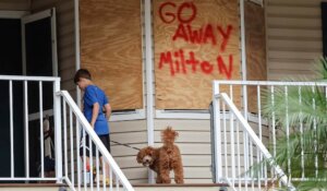 Noah Weibel and his dog Cookie climb the steps to their home as their family prepares for Hurricane Milton on Monday, Oct. 7, 2024, in Port Richey, Fla. (AP Photo/Mike Carlson)