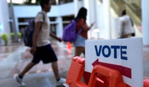 People walk past a Vote sign on the first day of early voting in the general election on Monday in Miami. (AP Photo/Lynne Sladky)