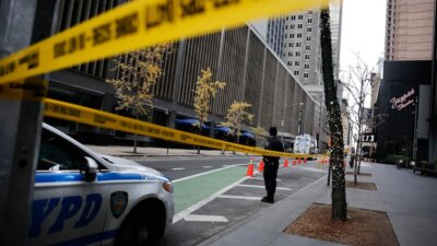 A New York police officer stands on 54th Street outside the Hilton Hotel in midtown Manhattan where Brian Thompson, the CEO of UnitedHealthcare, was fatally shot Wednesday, Dec. 4, 2024, in New York. (AP Photo/Stefan Jeremiah)