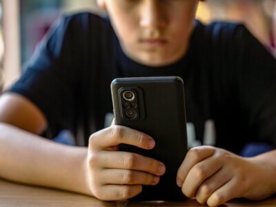 Child boy with cell phone, holds smartphone.