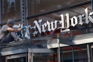 A man polishes the sign for The New York Times at the company's headquarters, July 18, 2013 in New York. (AP Photo/Mark Lennihan)